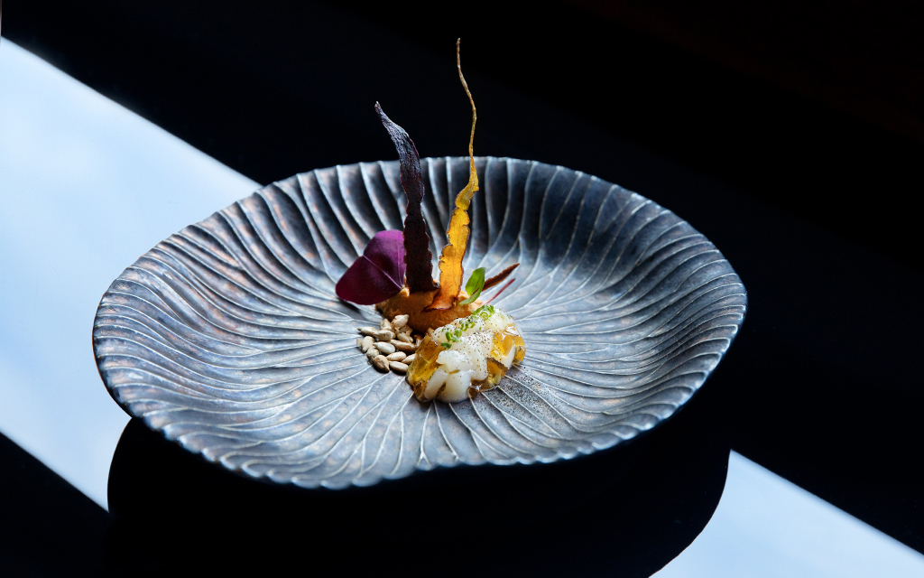 black organically shaped dish with scallop tartare and carrot puree